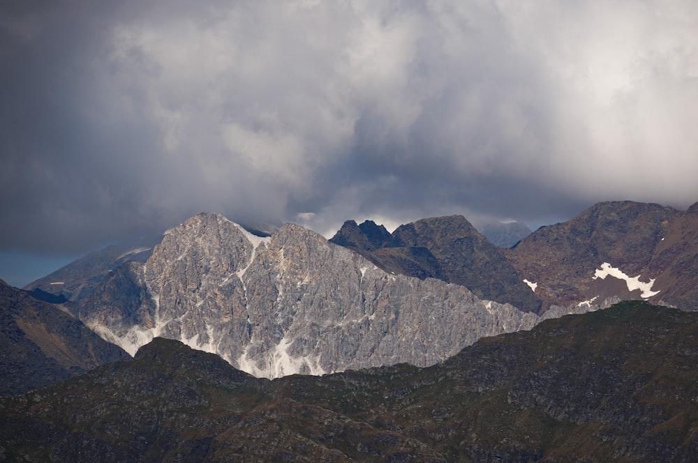 a group of mountains with snow on them under a cloudy sky