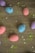Colorful speckled eggs in pink, blue, and purple are scattered on a wooden surface, surrounded by green and red sprinkles and white star-shaped decorations.