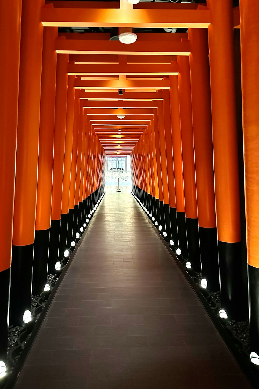 a long walkway lined with orange and black columns