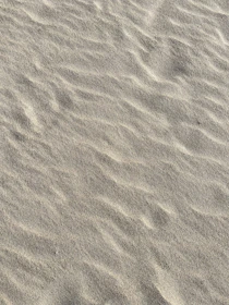 Smooth, fine sand cascading into a clean metal container under soft natural light.