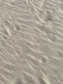 Smooth, fine sand cascading into a clean metal container under soft natural light.