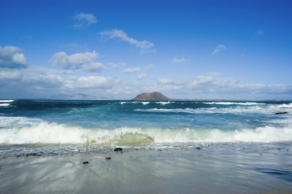 Surf, with an island offshore — Fuerteventura, Spain