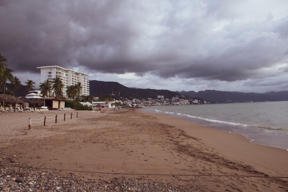 a cloudy day at the beach with a hotel in the background