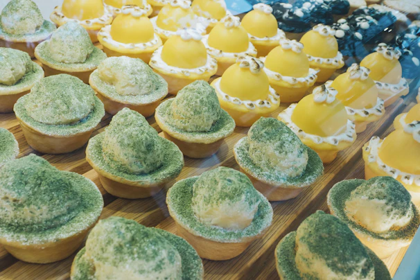 A display of freshly baked pastries and sweet treats next to a steaming cup of matcha latte.