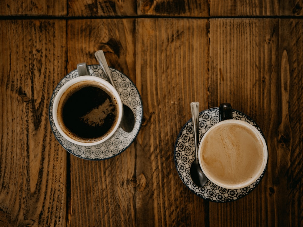 two cups of coffee sitting on top of a wooden table