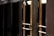 A close-up view of several gold-colored metal doors with vertical handles, set within a dark frame. The doors have reflective glass panels that are partially shaded, suggesting a quiet or closed-off environment. The lighting emphasizes the metallic sheen of the door handles and frames.