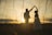 A happy couple dancing at their wedding with a beautiful sunset in the background.