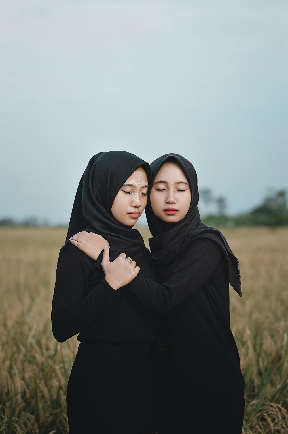 duas mulheres abraçando em um campo de grama alta