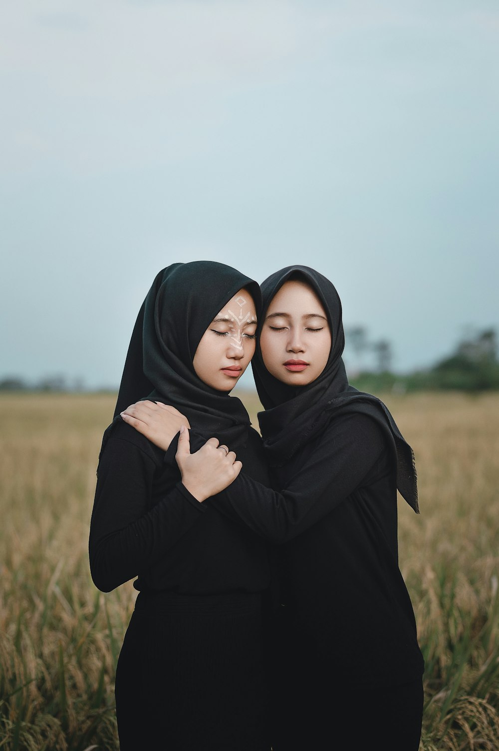 two women hugging in a field of tall grass