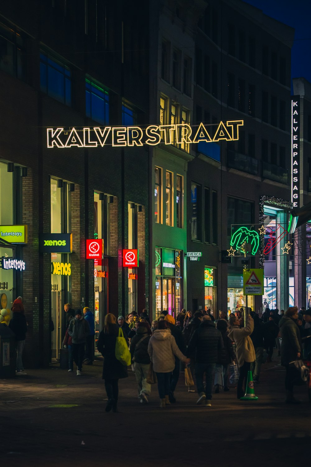 a crowd of people walking down a street at night