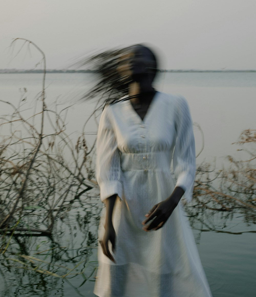 a woman in a white dress standing in front of a body of water