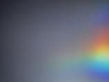 A gradient gray background with a soft, semi-transparent rainbow appearing primarily on the right side, blending smoothly into the surrounding area.
