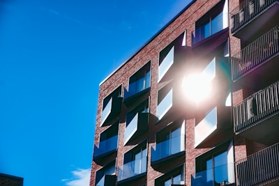 Modern apartment building facade with balconies and large windows in a sunny neighborhood.