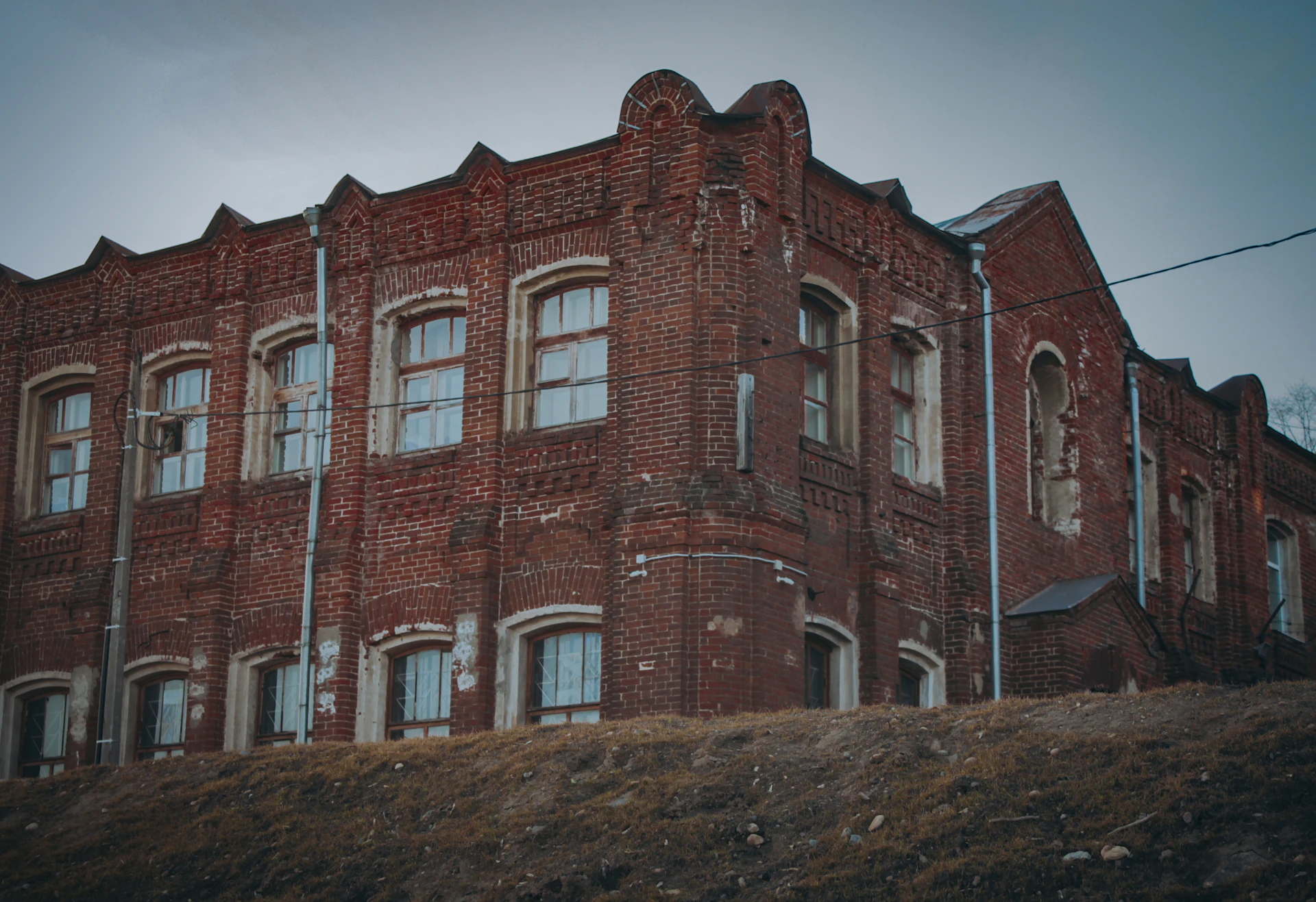 an old red brick building on a hill