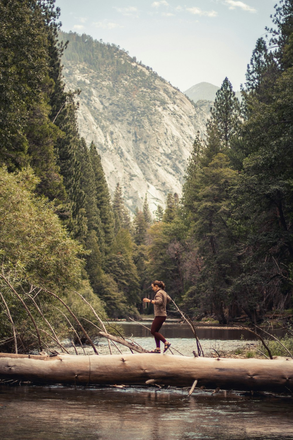 a person crossing a river on a log