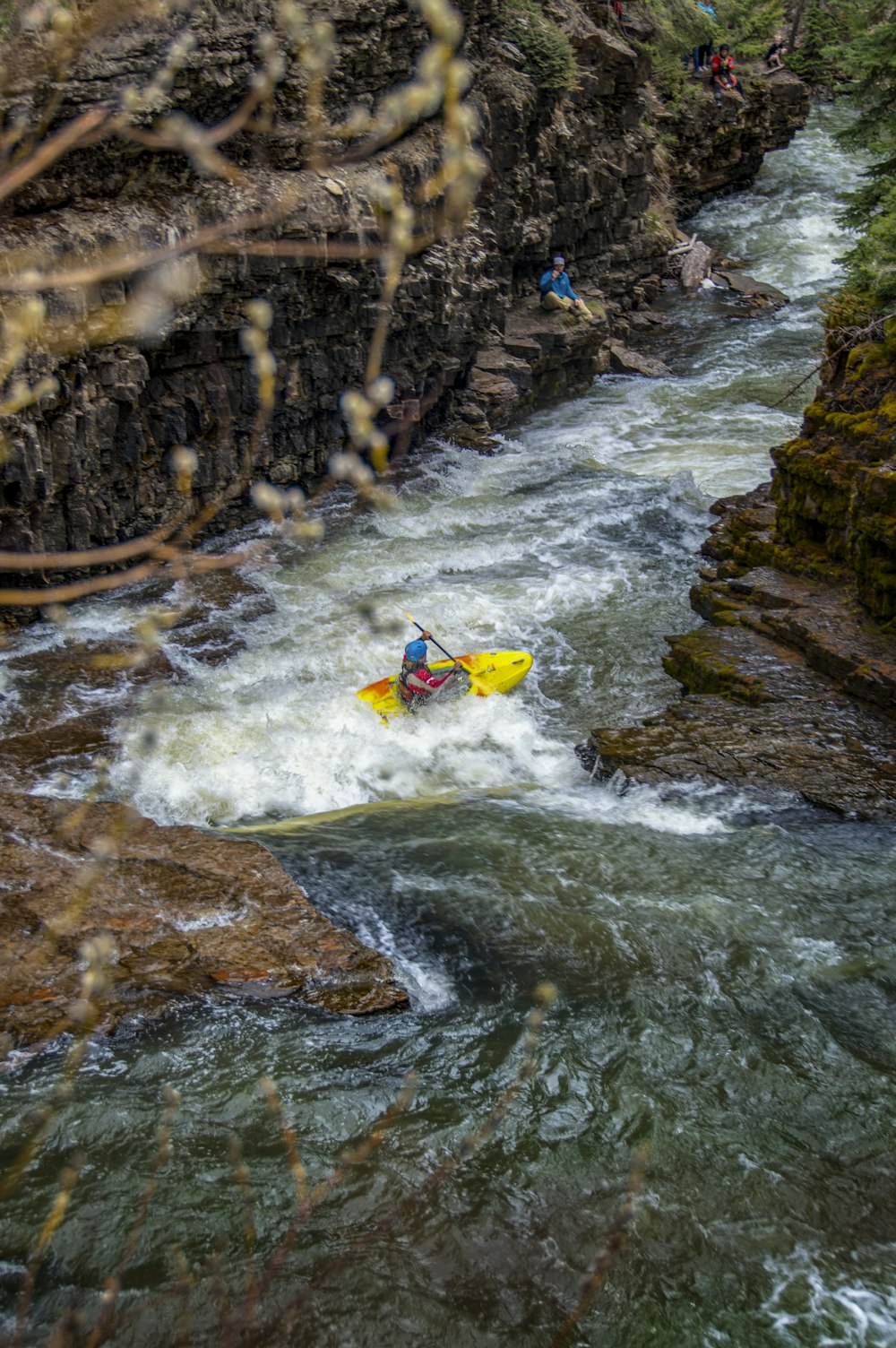 a man riding a yellow kayak down a river