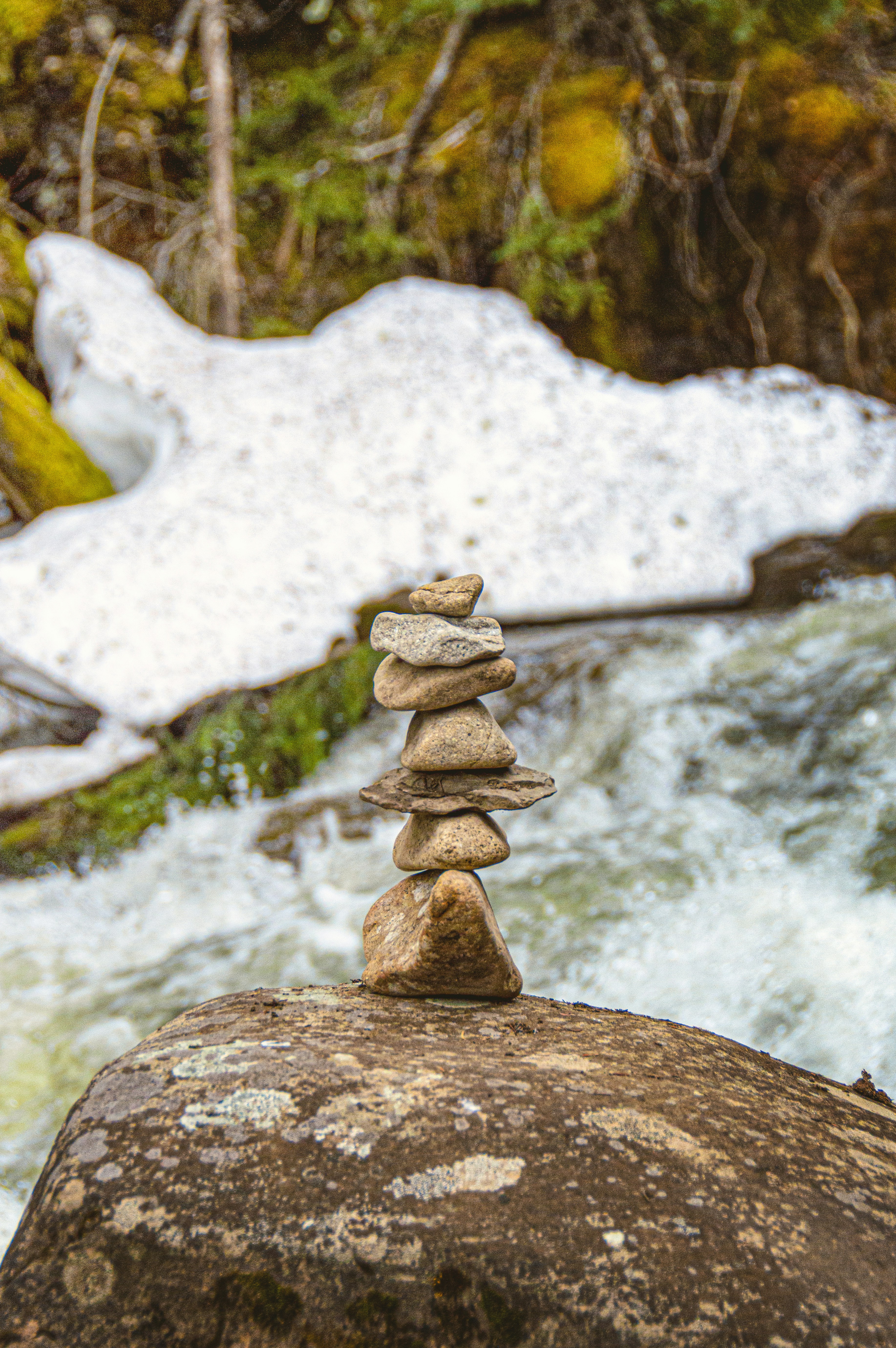 A stack of rocks sitting on top of a rock next to a river photo – Free ...