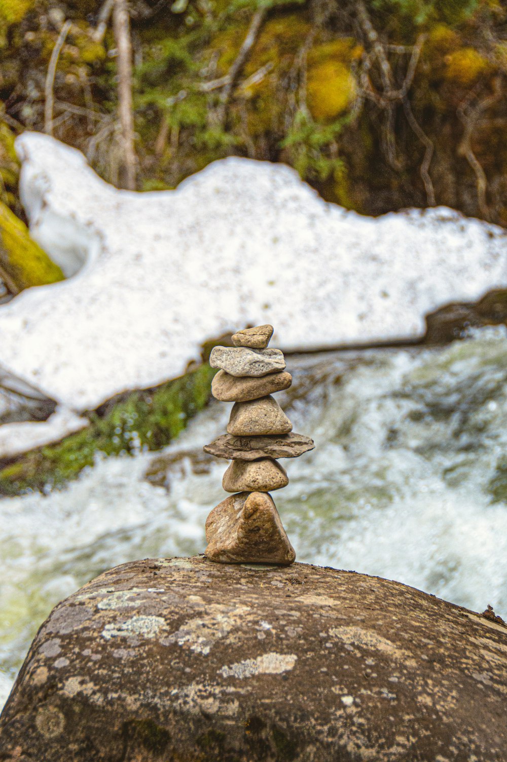 a stack of rocks sitting on top of a rock next to a river