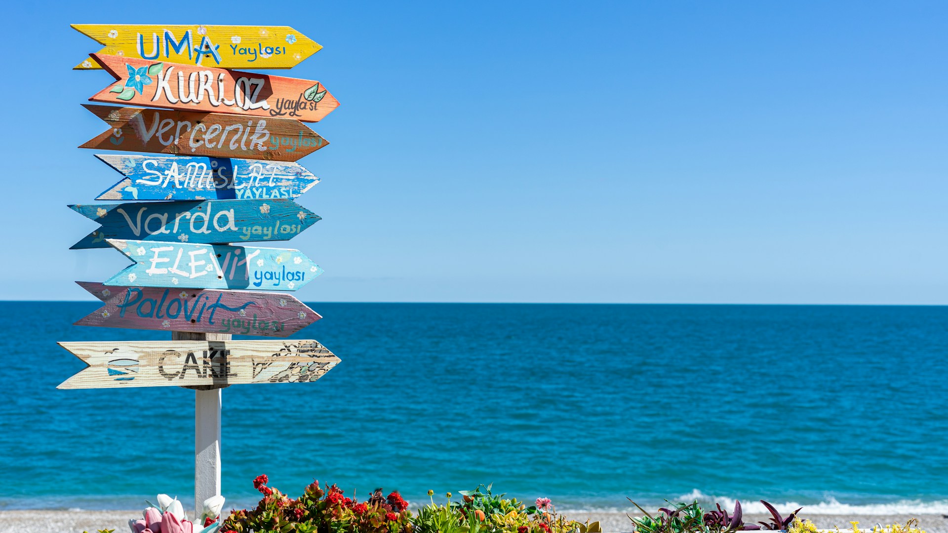 a wooden sign sitting on the side of a beach