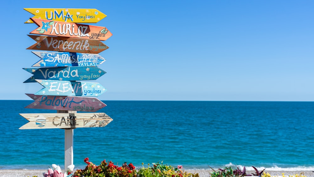 a wooden sign sitting on the side of a beach