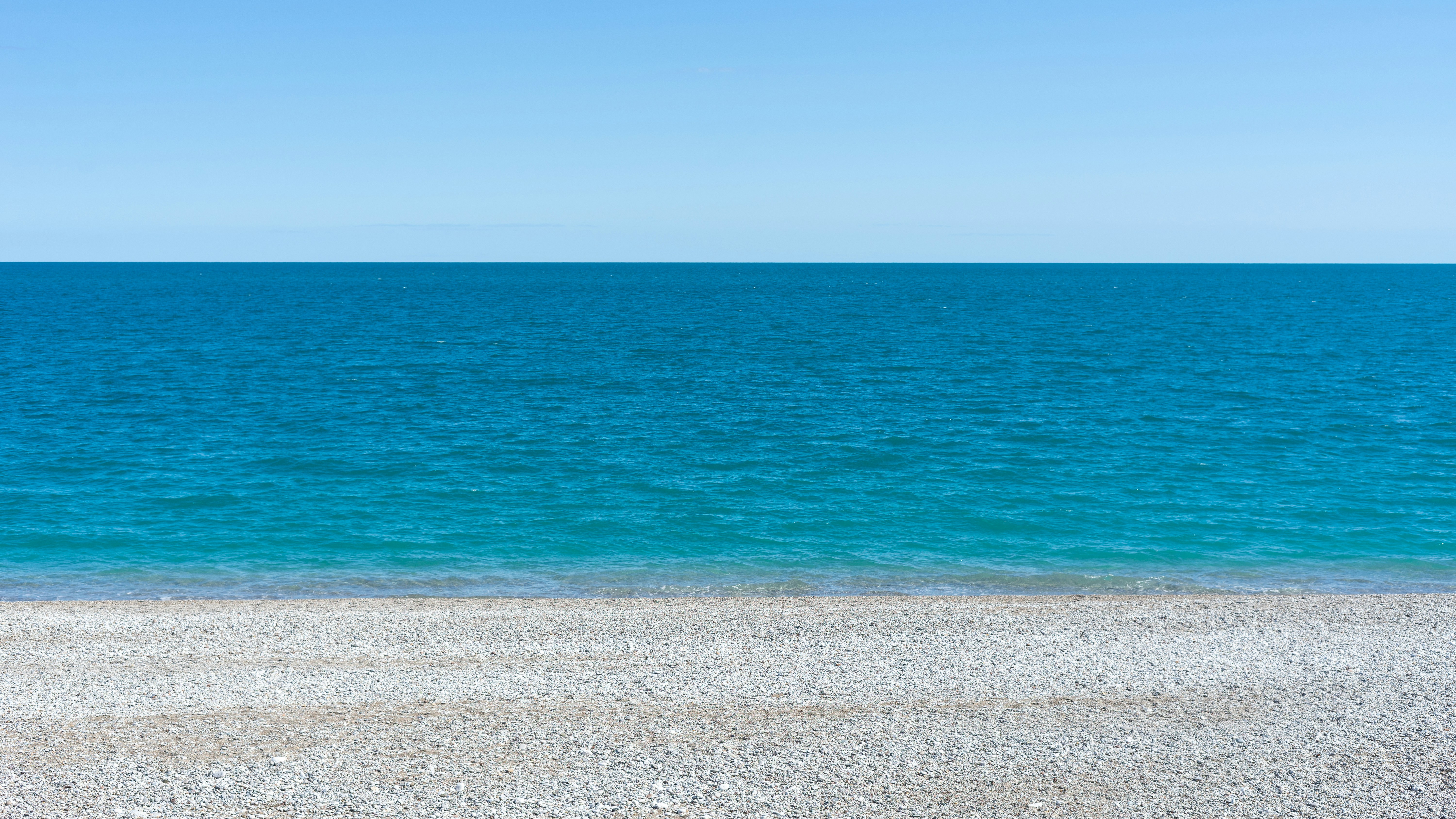 a bench sitting on top of a sandy beach next to the ocean