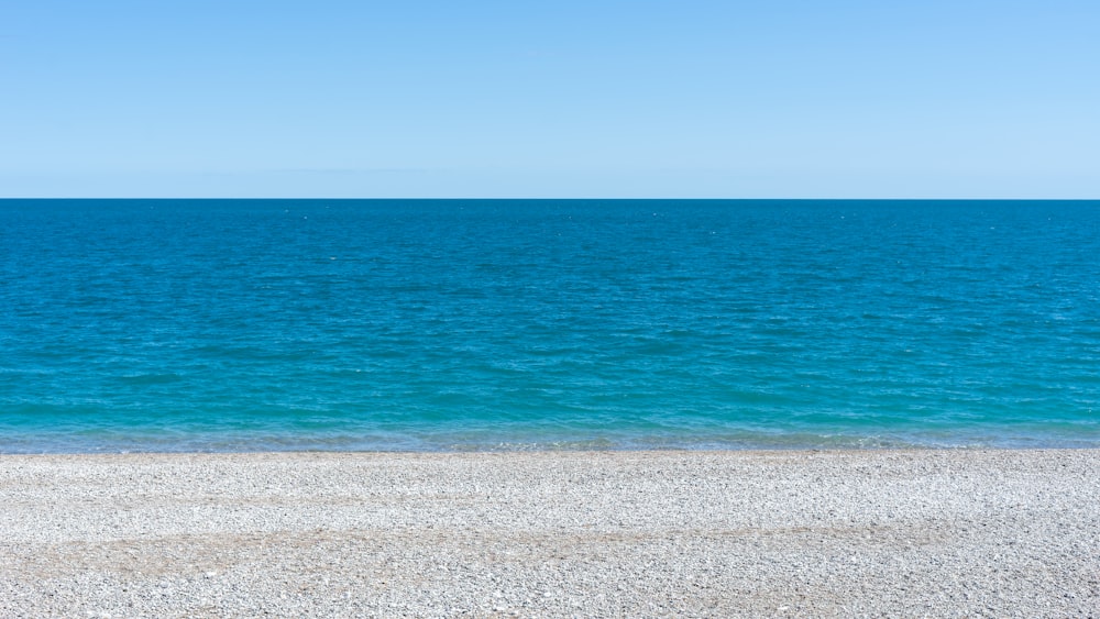 a bench sitting on top of a sandy beach next to the ocean