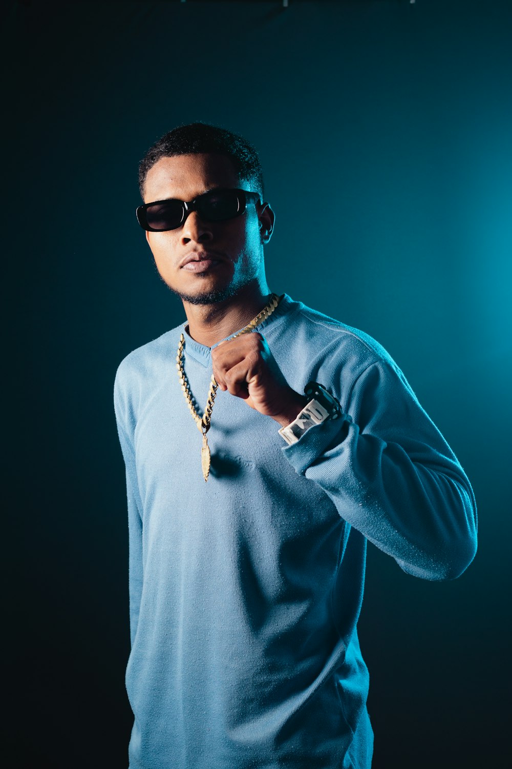 a man in a blue shirt and sunglasses posing for a picture