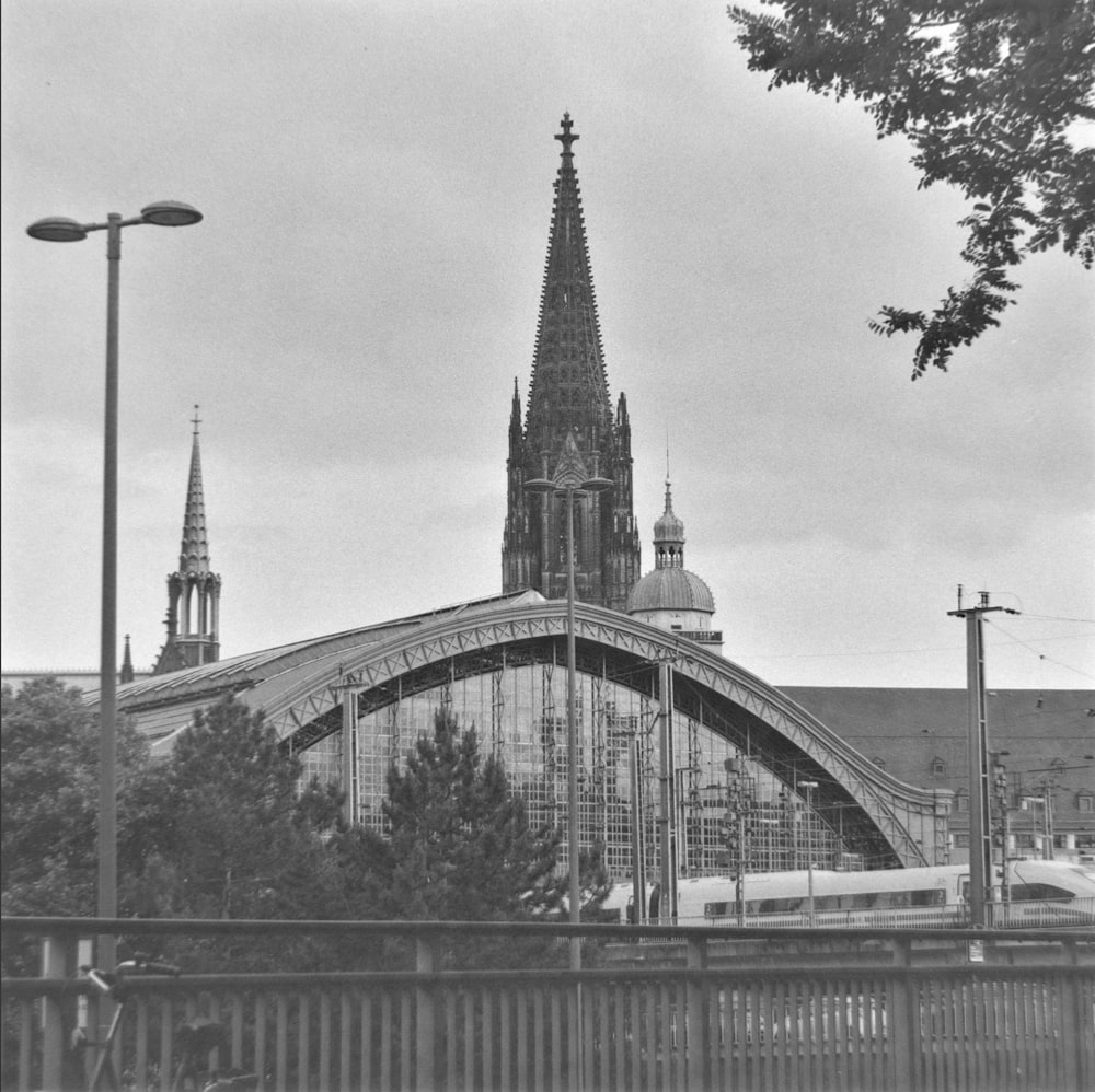 a black and white photo of a train passing by a cathedral