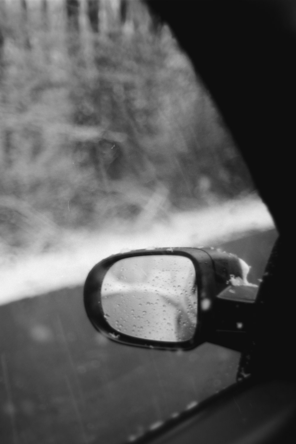 a side view mirror on a car with trees in the background