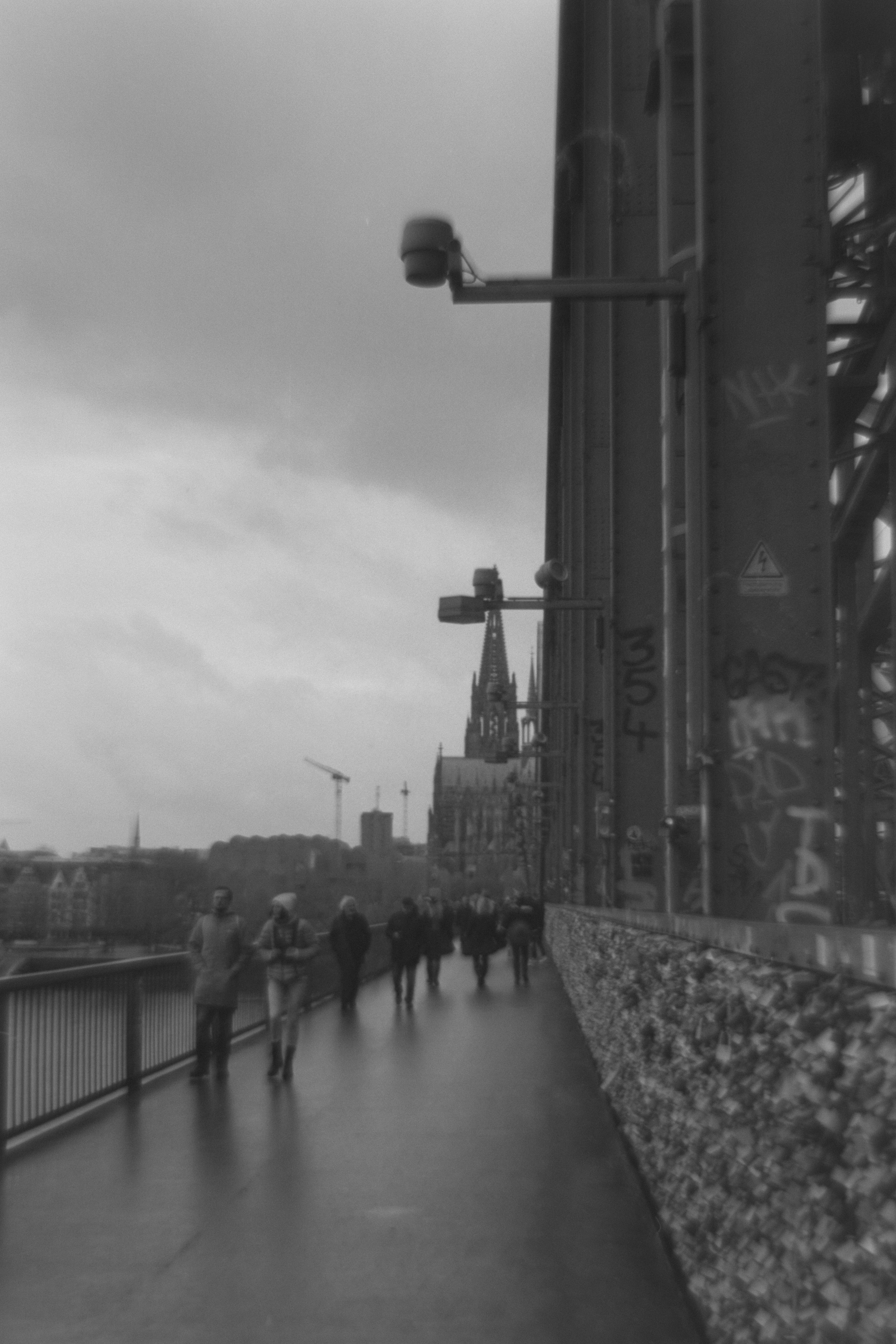 Une photo en noir et blanc de personnes marchant sur un pont