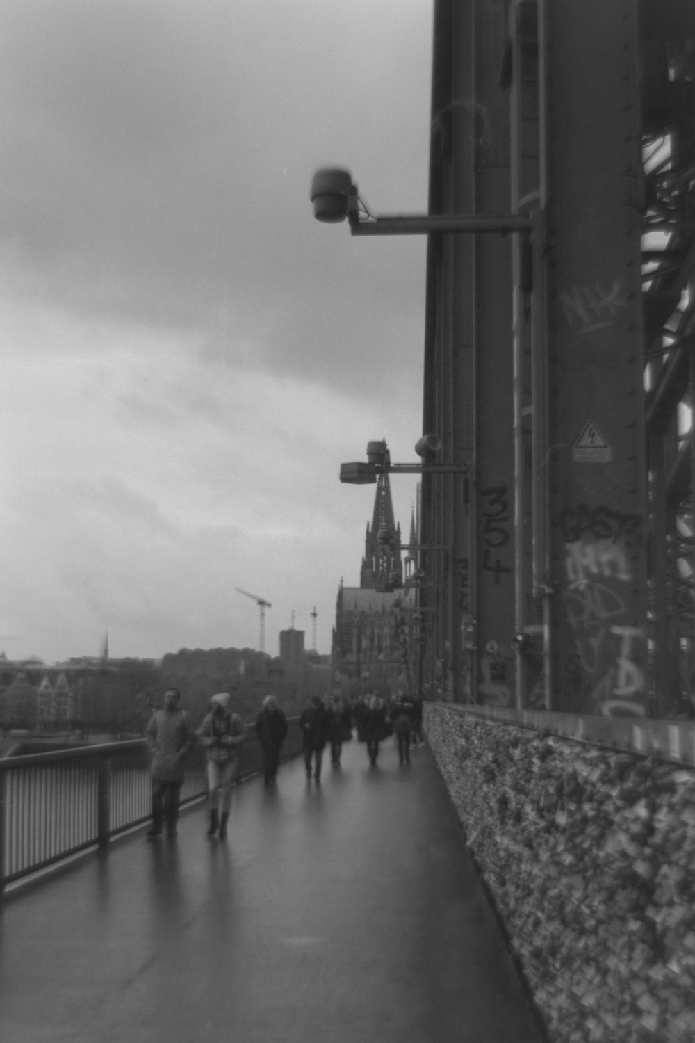 a black and white photo of people walking on a bridge