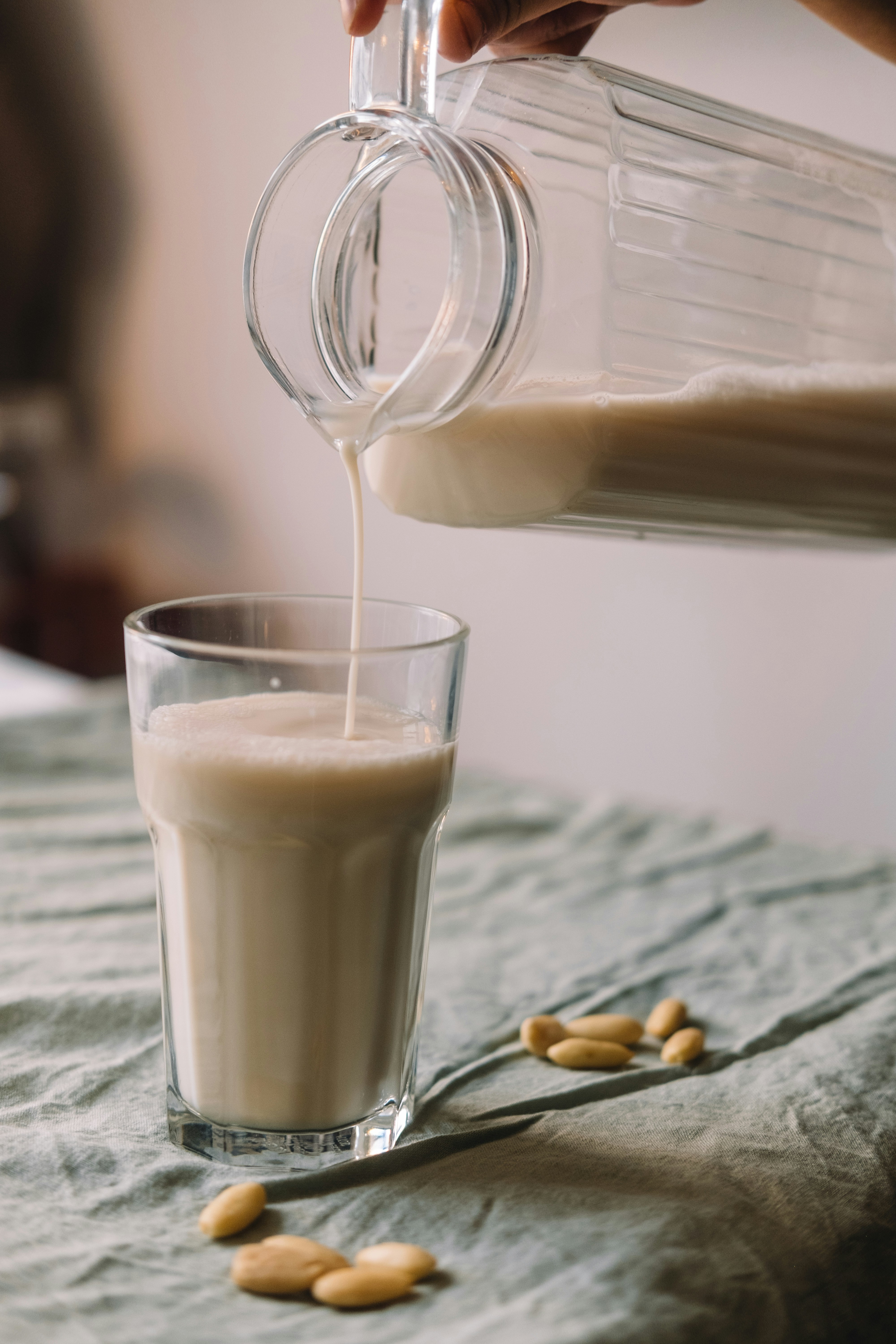 a person pouring milk into a glass on top of a bed