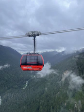a red cable car in the middle of a mountain