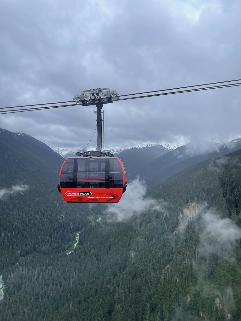 a red cable car in the middle of a mountain