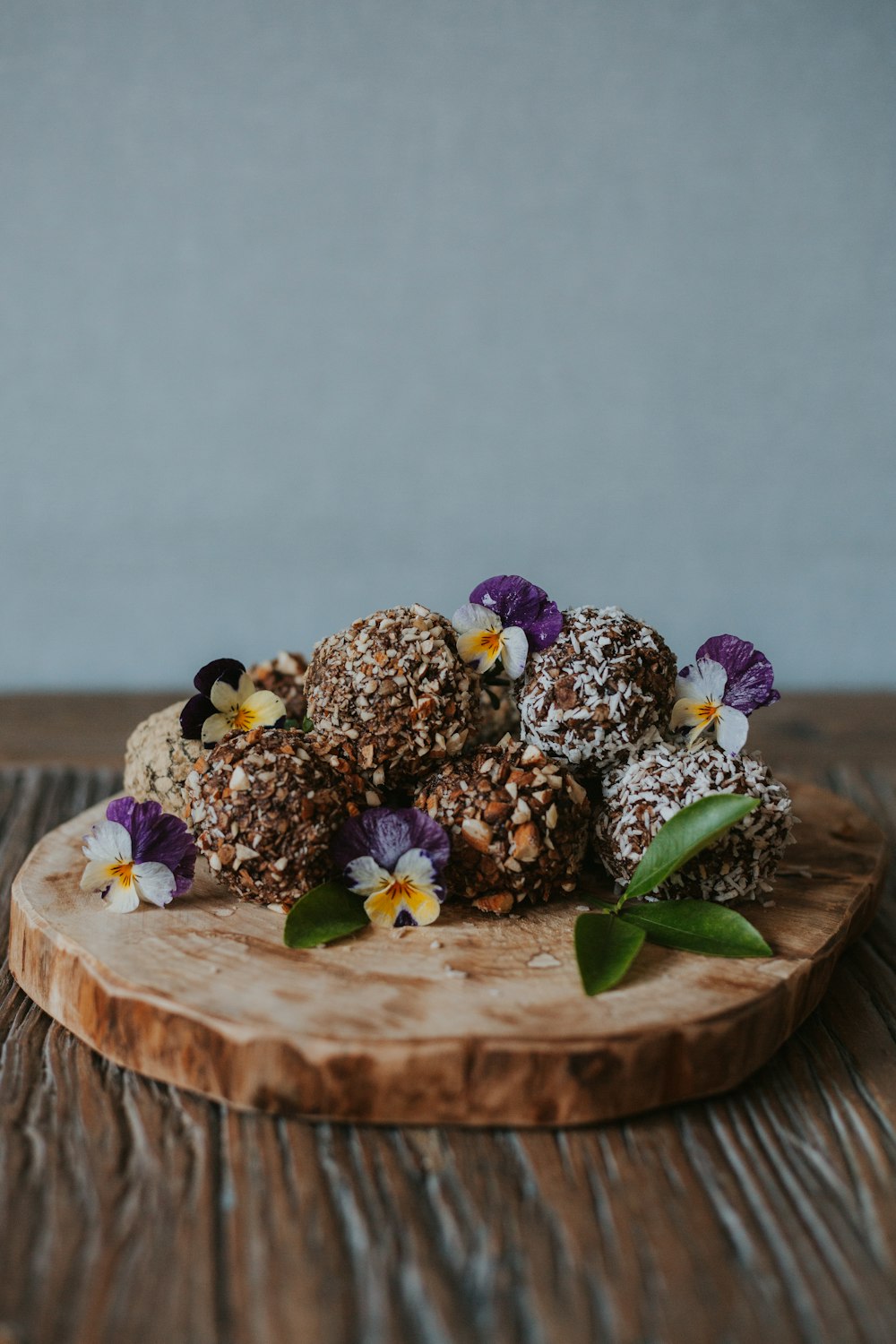 a wooden plate topped with chocolate covered donuts