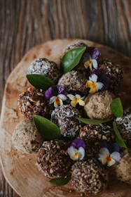 Elegant display of assorted Godiva truffles beside delicate Edo sushi rolls on a wooden platter.