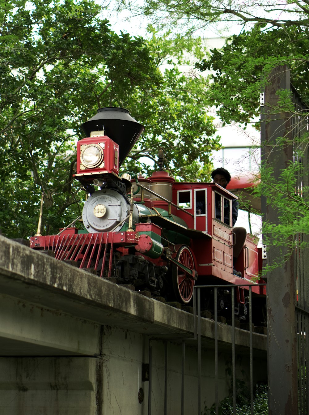 a red train engine sitting on top of a bridge