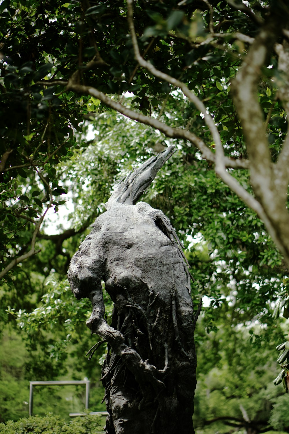 a statue of a bird sitting on top of a tree stump