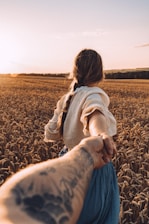 a woman holding the hand of a man in a field