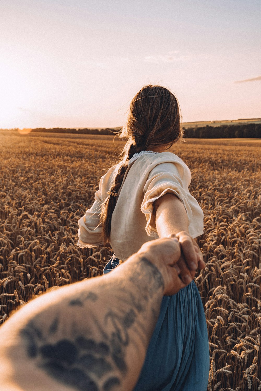 a woman holding the hand of a man in a field