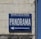 A blue sign on a brick wall with the words 'TOURING-CLUB DE FRANCE' in small letters and 'PANORAMA' in large letters, accompanied by an arrow pointing left.