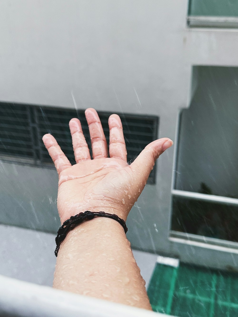 a person's hand reaching out of a window in the rain