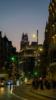 a busy city street at night with a clock tower in the background