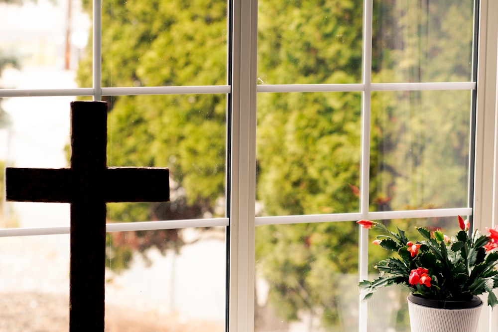 a cross and a potted plant in front of a window
