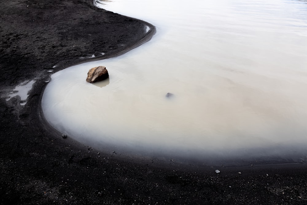 a rock sitting in the middle of a body of water