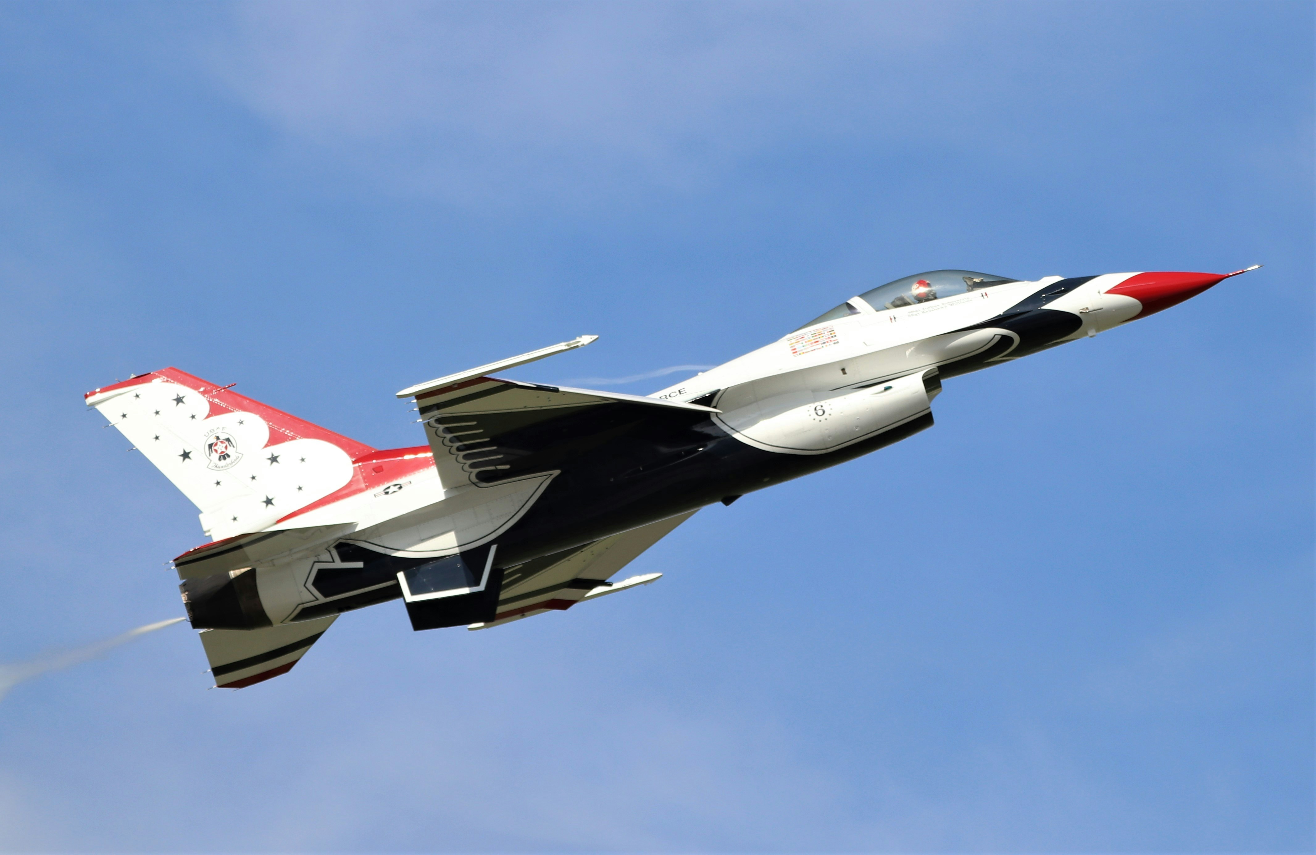 a fighter jet flying through a blue sky