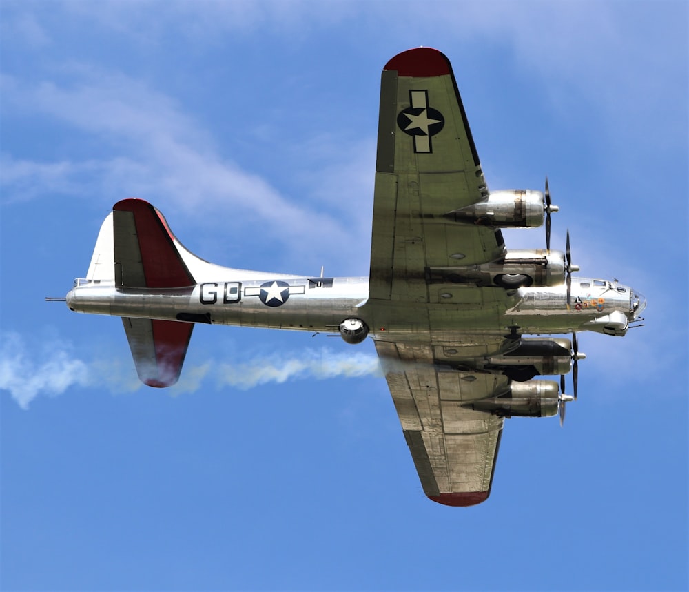 a silver and red airplane flying through a blue sky