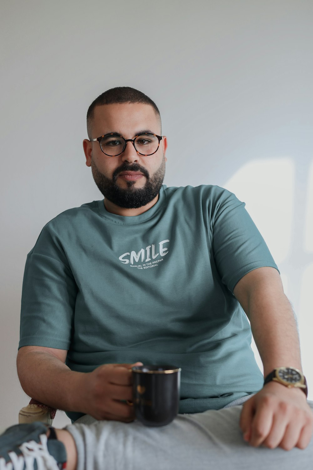 a man sitting on a bed holding a cup of coffee