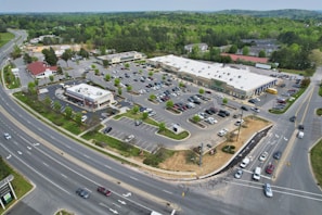 Sweeping drone footage of a commercial area with shops and parking lots.