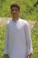 A casual outdoor shot of a man in off-white traditional wear, embodying simplicity.